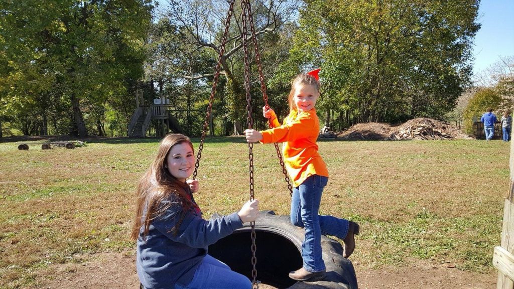 a mother and daughter enjoy a spin on the tire swings