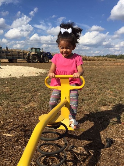 child rides playground equipment outside