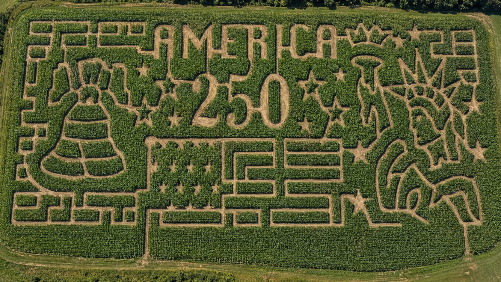 The word "America" centered in a corn field with the cracked Liberty Bell on the left, and American Flag in the middle, and the Statue of Liberty to the right.