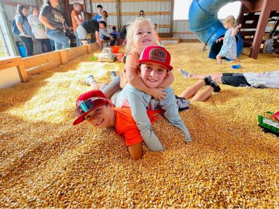 two children playing in a pile of dried corn