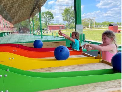 two children play a game of rolling a bowling ball up a ramp