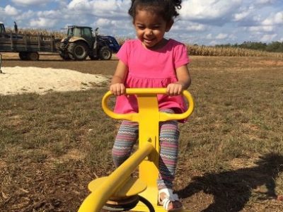 child rides playground equipment outside